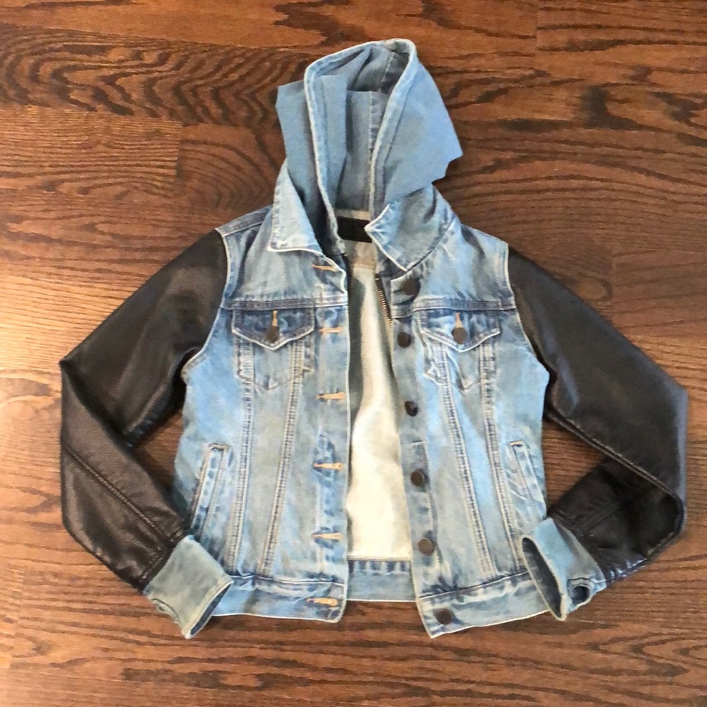 Jean jacket with black pleather sleeves.